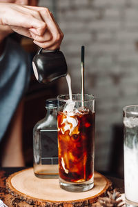 Close-up of hand pouring drink in glass on table