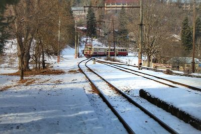 Snow covered railroad tracks by trees during winter