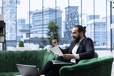 Young man using laptop while sitting in city