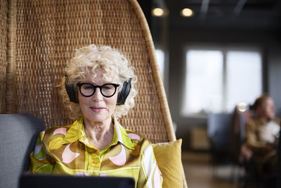 Senior woman with headphones using tablet in cafe