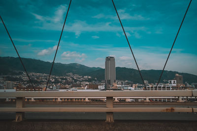 Bridge by buildings against sky in city