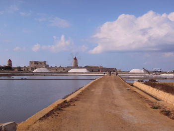 Walkway leading towards salt basin against sky