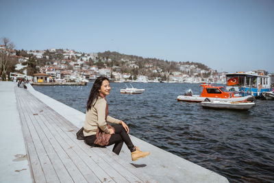 Rear view of woman sitting on pier