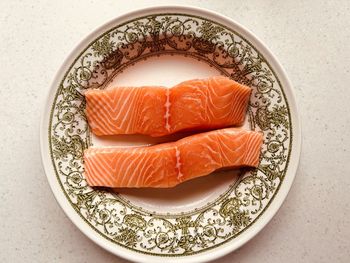 Overhead shot - 2 fresh salmon fillets. pinky orange fish. in ornate green and white plate.