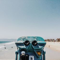 Close-up of coin-operated binoculars on beach against clear sky