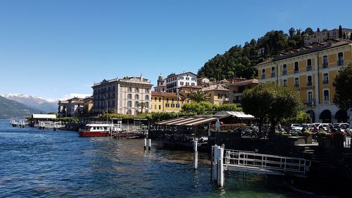 Houses by river against clear blue sky