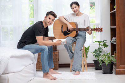 Happy woman playing guitar at home