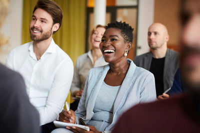 Smiling male and female entrepreneurs sitting in conference meeting at workplace