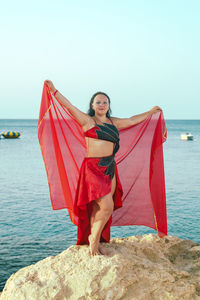 Portrait of woman sitting on rock at beach