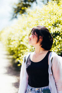 Young woman standing against tree