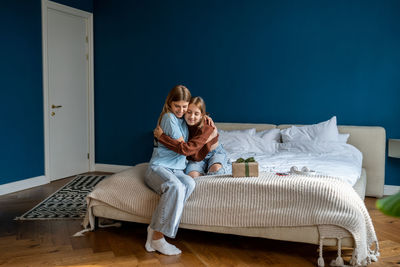 Young woman sitting on bed at home