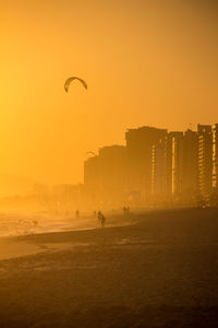 Scenic view of beach in city against clear sky during sunset