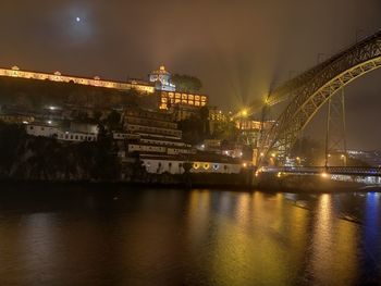 Illuminated bridge over river against sky at night