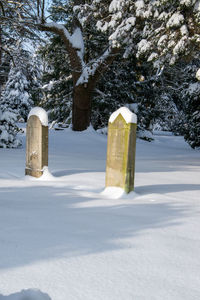 Snow covered cemetery against trees on field