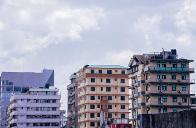 Low angle view of buildings against cloudy sky