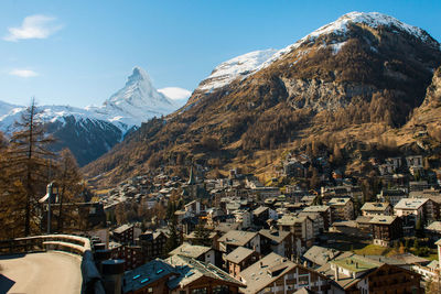 Aerial view of townscape by mountain against sky