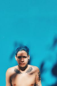 Portrait of young woman standing against blue wall