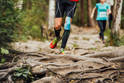 Male runner run forest race on knee kinesio tape