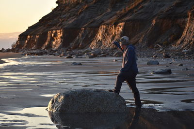 Rear view of man standing on rock at beach