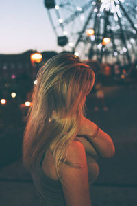 Rear view of woman with illuminated hair in city at night