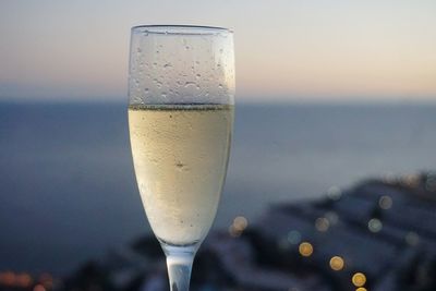 Close-up of champagne glass against sky during sunset