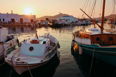 Boats moored in harbor at sunset