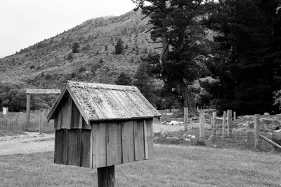 Old barn on field against trees and mountains