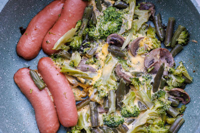 Fried sausages and vegetables with mushrooms and chicken egg on skillet