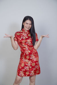 Midsection of young woman standing against red background