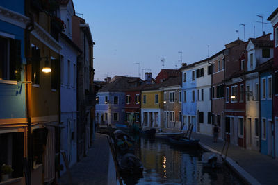 Canal amidst illuminated city against clear sky