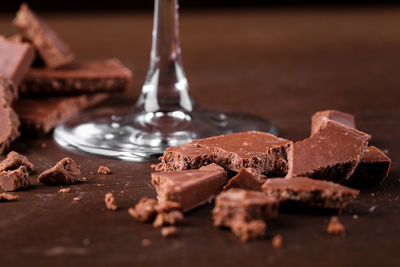 Close-up of broken chocolate by glass on table