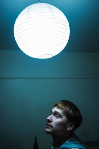 Portrait of young man looking at illuminated lamp