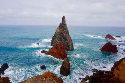 Rock formation on sea shore against sky