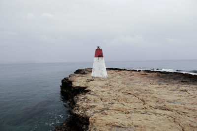 Lighthouse by sea against sky