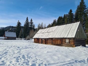 House on snow covered field against sky