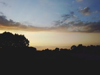 Silhouette trees on landscape against sky during sunset