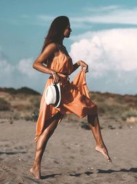 Side view of woman wearing sunglasses on beach against sky