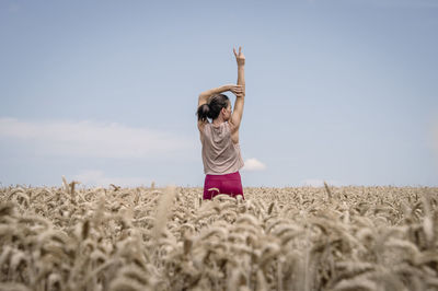 Full length of woman with arms raised standing on field