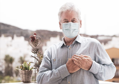 Portrait of senior man wearing mask standing outdoors