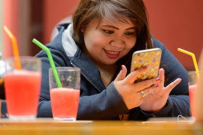 Portrait of young woman sitting on table at restaurant