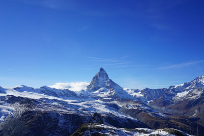 Scenic view of snowcapped mountains against blue sky