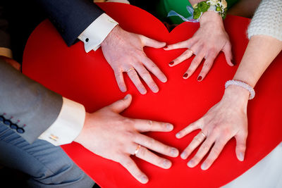 Cropped hands of couples on heart shape card