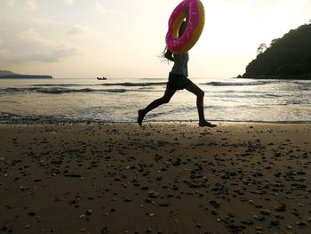 Full length of woman on beach against sky during sunset