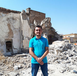 Portrait of smiling young man standing against built structure