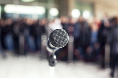 Close-up of microphone with people standing in background