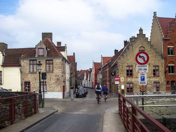 Rear view of man walking on road amidst buildings in city