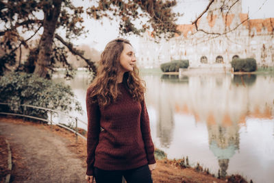 Happy woman posing in red sweater in the park by the new town hall in hannover, germany