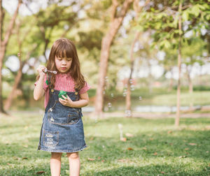 Full length of cute girl holding plant on field