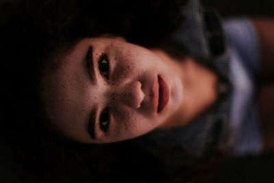 Close-up high angle view of young woman resting in darkroom