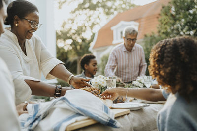 Happy male and female family members having lunch during family gathering at garden party
